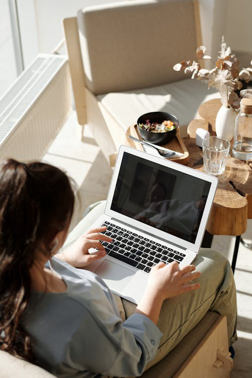 A woman is using a laptop while sitting on a chair