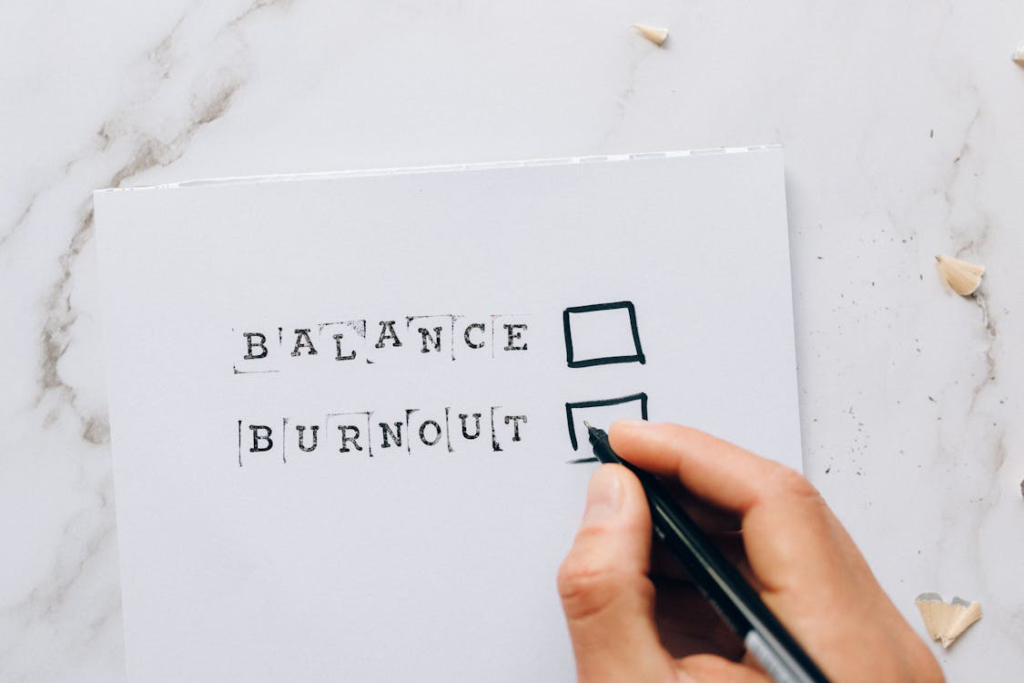 A person is writing on a white sheet that says “Balance, Burnout”